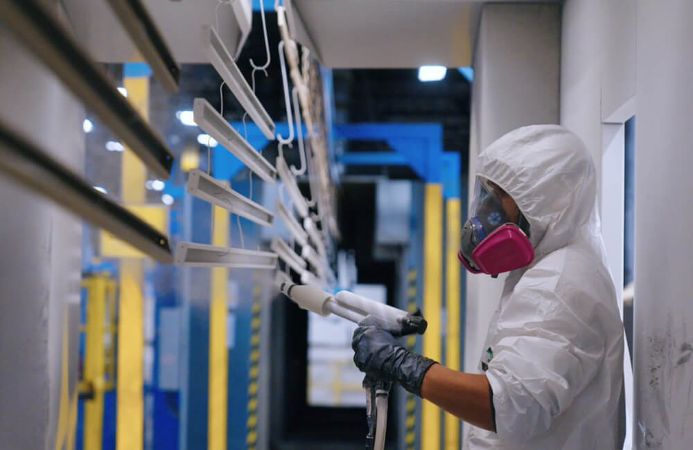 man in a white garment spray coating metal materials